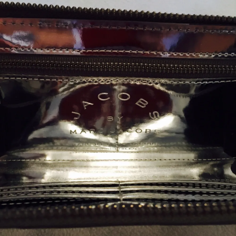 Helt ny äkta Ltd Edition Marc Jacobs plånbok som aldrig kom till användning. Svårt att fota eftersom den är glansig/ spegel effekt. Får plats med 6 kort och har en mynt hållare. 
Mått : B 19cm H 10cm D 2,5cm. Frakt 35kr. . Accessoarer.