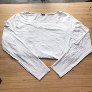  - Långärmad tröja i stretchigt material. Avklippt i ärmar och längst ner vilket ger fint rullade kanter