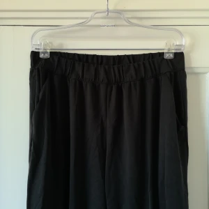  - Mörkgrå byxor i hög modell och resår i midjan. Syntet