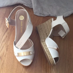  - Snygga sommarskor River Island. Vita med detaljer i guld. Nästan oanvända. Nypris 600kr. 