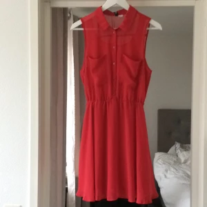  - Superfin klänning från HM med knappar fram och fint fall i en klarröd färg.Passar 34-38. Som ny.