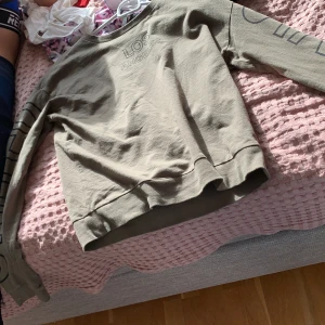 Grön långärmad  - En grön långärmad tröja med los angeles tryck på framsidan över bröstet och text på ärmarna. 