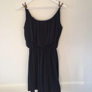  - Klänning i dubbelt tyg med markerad midja. Bruna axelband. 