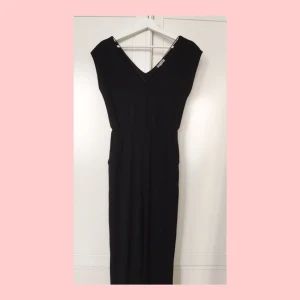  - Svart byxdress, hellånga ben, fickor framtill, väldigt snygg passform med snören över brösten. Inköpt i New York, sparsamt använd och i mycket fint skick!