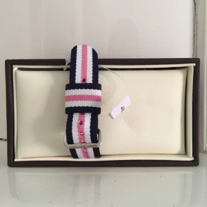  - Randigt natoband i rosa, vitt och blått som kommer från Daniel Wellington. Bandet är 18mm och passar till damklockorna med 36mm boettbredd. Bandet är helt oanvänd och ask ingår. 