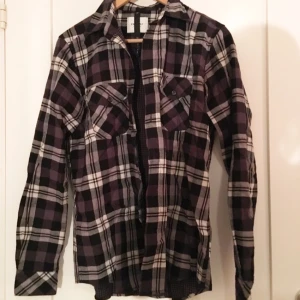  - Skjorta av ganska tjock material (väldigt härlig i vintertider) med svart/vitt/grått-rutigt mönster på utsidan och svart/grått-rutigt mönster (små rutor dock) på insidan! Från Vailent