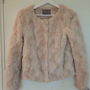 - Puderrosa/beige päls (fuskpäls). 
Väldigt mjuk och bekväm att bära