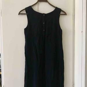 Enkel liten mörkblå/svart klänning från Gudrun Sjödén i storlek S. Den har knappar i ryggen och en extraknapp om en skulle försvinna. I nyskick då den knappt är använd. 100% viskos 