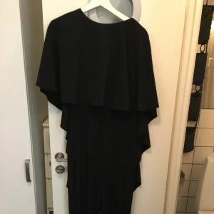  - Världens finaste byxdress som är väldigt svår att fånga på bild. Framtill går en stor volang som följer med ut på ärmarna, ryggen är helt öppen. Mycket fint skick!