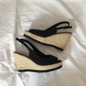  - Klackskor med kilklack, man kan ändra storleken på bandet vid hälen. 