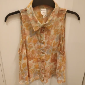 Blommig sheer topp  - Jättesöt topp i ljusrosa/orange/vit. Den är lite croppad. Så fin under en tröja med kragen! Storlek S.