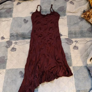  - Mörklila klänning i strl 36, använd men i fint skick! Snörning på ryggen och tyget är i 100% polyester. Obs att en söm har gått sönder längst ner på volangen men syns inte så tydligt.