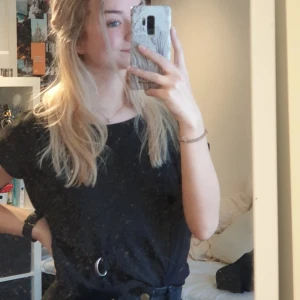 Tröja från kappahl - En svart tröja med två silverringar fastsydda på höger framsida av tröjan