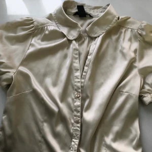 Silkesskjorta - Beige silkesskjorta med kort puff-ärm. Skjortan är figursydd och ger en fin form