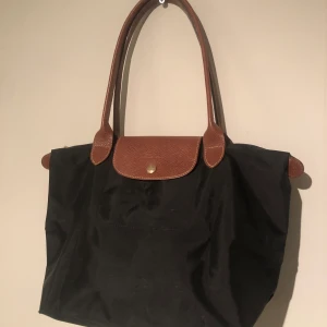 Longchamp väska - En fin Longchamp väska i svart. Väskan är i måtten 34x24 och i väldigt fint skick. Kontakta för mer information.