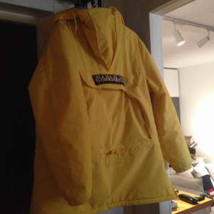 En napaijir jacka gul är mycket varm och skön i minus grader , fryser inte i den , har en öppning på sida. Och en luva samt en fixa i mitten av jackan köpt för ett år sedan är i mycket bra skick nypris 3100kr 
