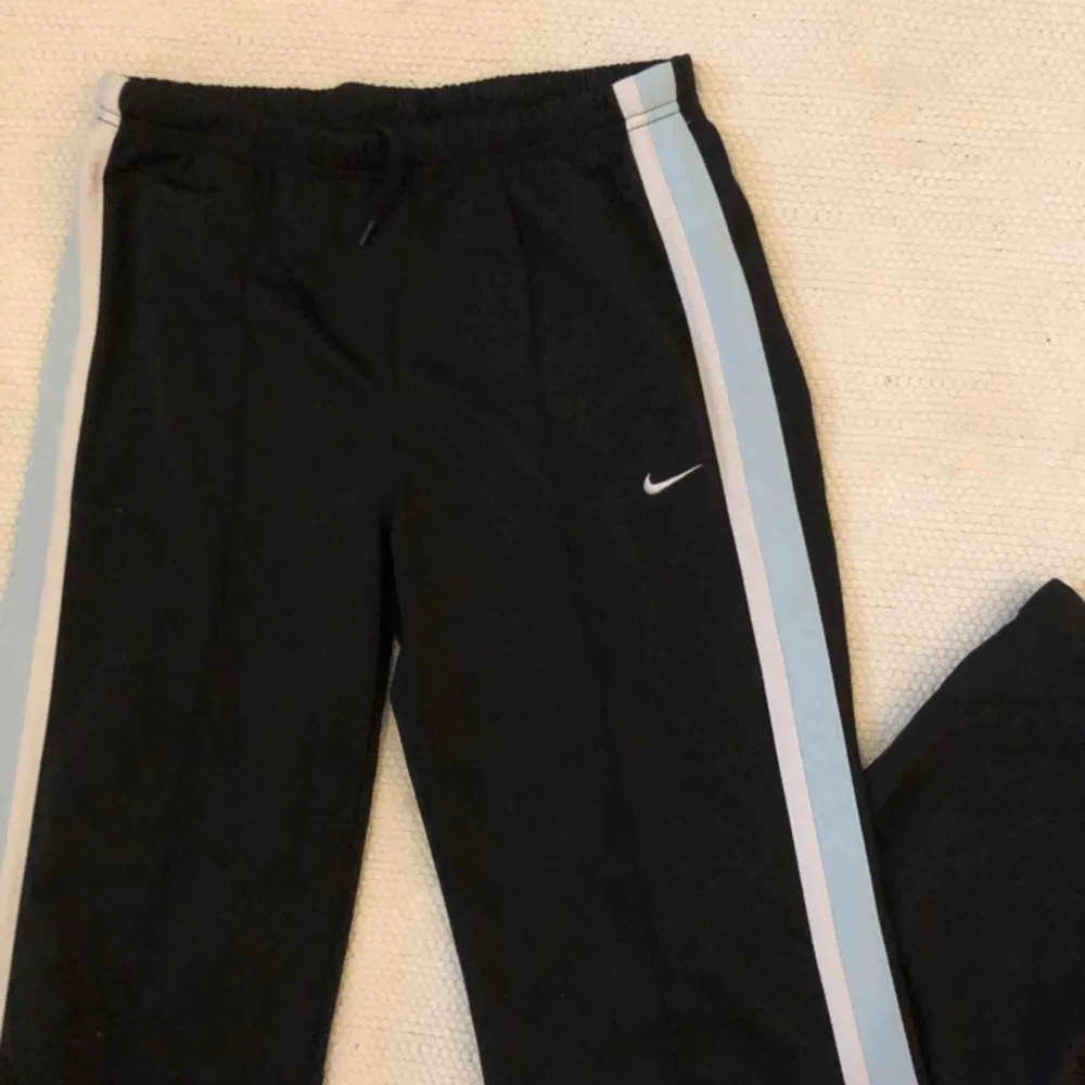 Svarta Nike trackpants men blåa och vita detaljer🦋. Jeans & Byxor.