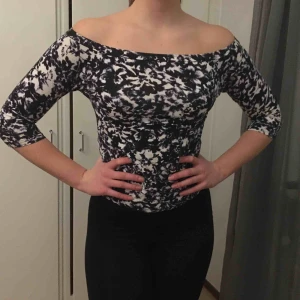  - Off shoulder tröja med ett mönster av blommor. Färgen är mörkblå och vit