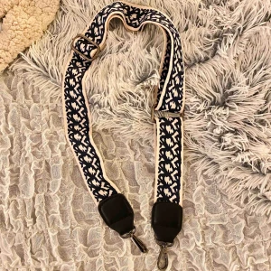  - Ett justerbart axelband till en väska ! Det är vitt med ett marinblått mönster, sen svarta detaljer och silvriga/gråa fästen. Möts upp i Linköping annars står köparen för frakt ❤️