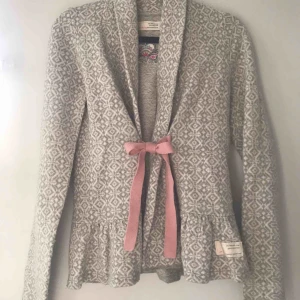 - Säljer en kofta från Odd Molly. Den är i storlek 0 vilket passar XS/S. Den har en knytning i rosa på framsidan och ett Odd Molly- märke i nacken. Material: 70% ull och 30% nylon.
