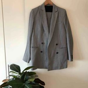  - Kritstrecksrandig kostym från J.Lindeberg. Pearl Wool Pin (kavaj) + Kori Wool Pin (byxa). Storlek 38 i kavaj och storlek 36 i byxor.  Använd med i mycket bra skick!  650:- för kavajen. 450:- för byxorna.  900:- för hela kostymen.