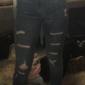 Skinny jeans med hål - Blåa skinny jeans med hål från HM. Byxorna sitter bra på mig, är omkring 1,60m lång. Men säljer för att byxorna inte kommer till användning.