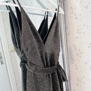 Lång metallic jumpsuit strl S - Säljer en jumpsuit från Forever21 i storlek S. Går ner till marken på mig som är 167. Har sytt ihop den lite så att urringningen inte är så djup (se bild 1). Knyte i midjan och är i stretchigt material. Aldrig använd!! Köparen står för frakt