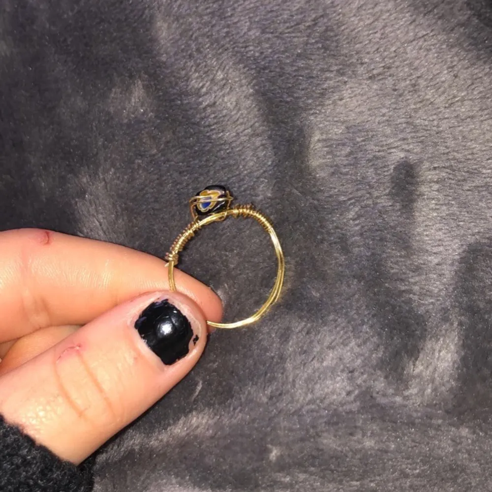 Säljer lite ringar som jag gjort själv, ringen är gjord av guldig ståltråd och en svart pärla/Sten med små blommor på. Säljer denna ring för 15 kr+ 11 kr i frakt. DMa mig vid intresse!. Accessoarer.