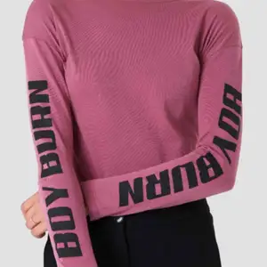 Rosa/lila långärmad tröja med ”BOY BURN” tryck på båda ärmarna från NA-KD! I storlek XXS men skulle säga att den är som en XS. ALDRIG använd och i NYTT skick!