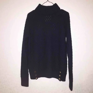  - Mörkblå stickad tröja med gulddetaljer nedtill, storlek M men sitter bra på en person som normalt sett har storlek S! Använd någon enstaka gång så är i väldigt fint skick!