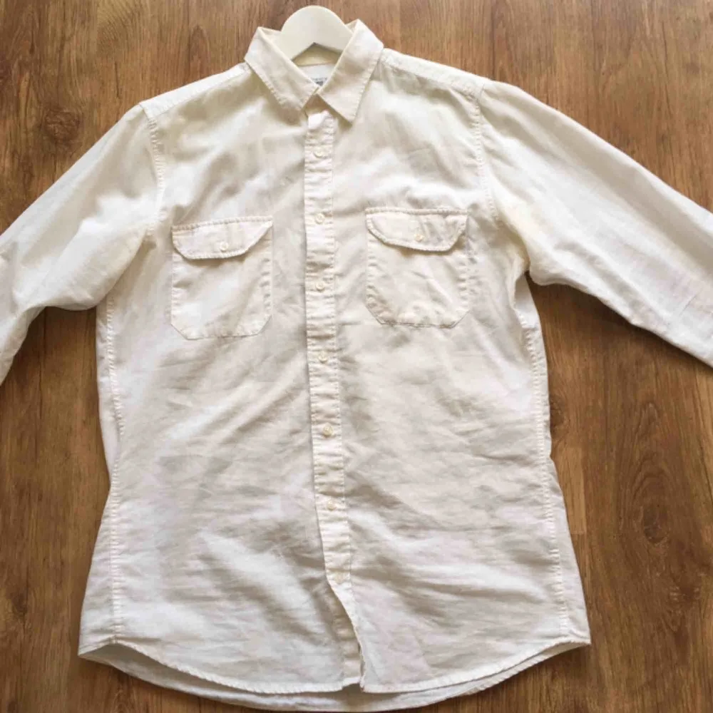 En vit skjorta i herrmodell. Den har 2 bröstfickor. . Skjortor.