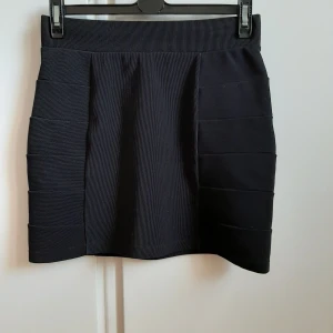 Svart enkel kjol - Kort, svart enkel kjol med lite ribbade sidor som gör den stretching när man går. Säljer pga att den inte används och är därför även i bra kvalitet. Passar till både t-shirt, skjortor och kavajer. Frakten står köparen för. 