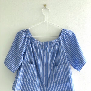 Randig offshoulder-blus  - Blus i skjortmaterial, är menad att ha som off shoulder. Går ej att knäppa upp. Har använts några gånger men är i ett bra skick. 