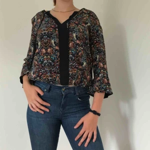  - Blommig blus med trekvartsärm med en volang i slutet av ärmen, sparsamt använd. Pris kan diskuteras.