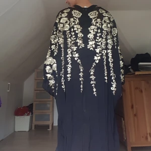  - One of a kind kimono i svart chiffong Med guldiga broderier Märkt som strl 34 men passar utan problem någon upp till M också.  Knälång på mig som är strax under 170