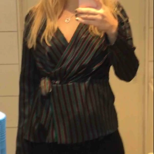  - Blus från Zara i stl L (sitter som en M). Den är randig i röd, grön och svart. Omlottblus som stängs med en dold knapp och knyts med band i samma färg och material. Köparen betalar frakt eller hämtar i Malmö 