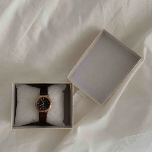  - Stilren och trendig unisex-klocka. Klockan har en svart urtavla, brunt band och guldfärgad boett.   Betalning görs via swish :) Fri frakt. 