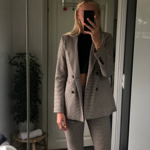 Rutigt Kostymset  - Köpt på Ginatricot. Kan även säljas separat. Byxorna är i 36, kavajen är i 38. Köptes för ca 1000kr totalt (kan ej hitta exakta priser då det är slutsålt). Jag säljer de för 500 kr + frakt. Byxorna säljer jag för 150kr separat då dom är lite noppriga på innerlåren. Kavajen är aldrig använd så den är i nyskick. (Jag är 180 cm lång)