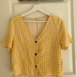 Gul rutig blus  - Gul och vit rutig blus med knappar framtill.
