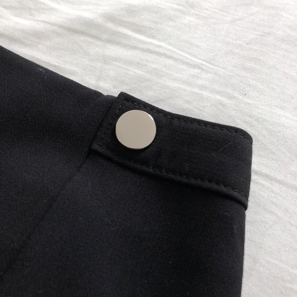 En snygg tajt svart minikjol från H&M. Dekorativa knappar på framsidan. Aldrig använd så i superfint skick! Frakt på 44kr tillkommer om den ska skickas!. Kjolar.
