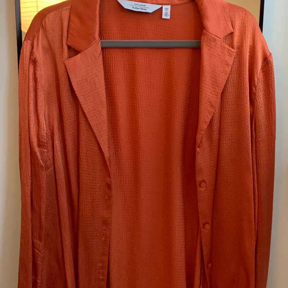Orange satinskjorta från & Other Stories i storlek 36. Använd ca 2 ggr och i fint skick. Skickas spårbart med Schenker.. Blusar.