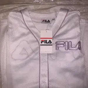 En jättefin fila baseball T-shirt som stängs med knappar, Fila loggan sitter på både bröstet o ryggen. Storlek XS men är stor i storleken. Säljer den pga den inte passar mig och kan inte lämna tillbaks den då jag fick den i present. Möts upp i Stockholm, köparen står för frakten🥰            ❗️Priset kan diskuteras❗️