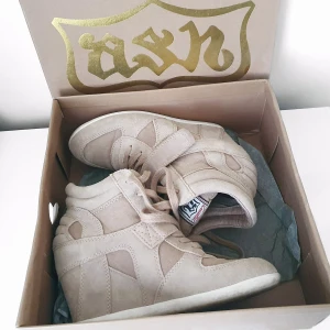 Ash sneaker kilklackar 37 - Färg: beige.  Strl: 37.  Snygga sneaker med klack från Ashitalia/ Ash. Använda, i gott begagnat skick enligt bilder. Klackhöjd ca 7cm. Tillhörande kartong medföljer. (Nypris 2000kr) Kommer ej till användning och stor garderobsrensning pågår!