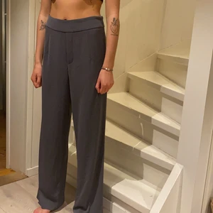 Vida kostymbyxor från BikBok - Vida, grå kostymbyxor från BiKBok i storlek M 🌺 hon på bilden är 170cm och bär vanligtvis storlek S. Väldigt fin passform, höga i midjan, lite längre och stretchiga 🌟 köparen står för frakten men jag kan även mötas upp i närheten 