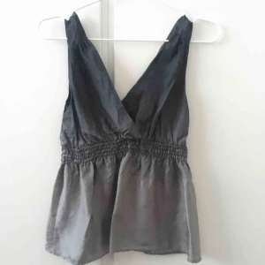  - Linne av 100% silke i svart och grått. Skärningen är samma fram som bak med en designdetalj baktill. 