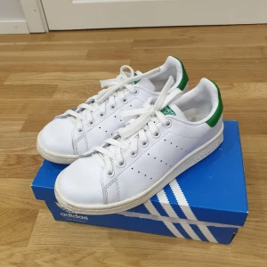 Adidas Stan Smith  - Ett par Adidas Stan Smith som är använda men i bra skick (se gärna bild för uppfattning om skick). Färg vit och grön, köpt på Nelly ett tag sedan. Originalkartong medföljs vid köp. Storlek 36,5 med innermått 22,5cm   Köparen står för frakt.  