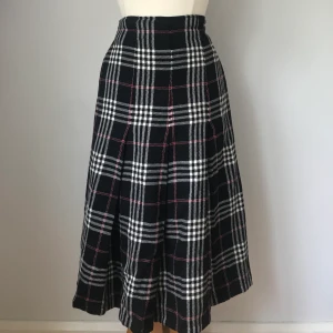 Rutig långkjol - Ser lite ut som en skotsk rutig kjol, med svarta vita och röda ränder med pressveck fram. Gott skick utåt men dessvärre har innerfodret rivits upp men det kan tas bort och plagget kan användas ändå. Storleken skulle jag säga är 36