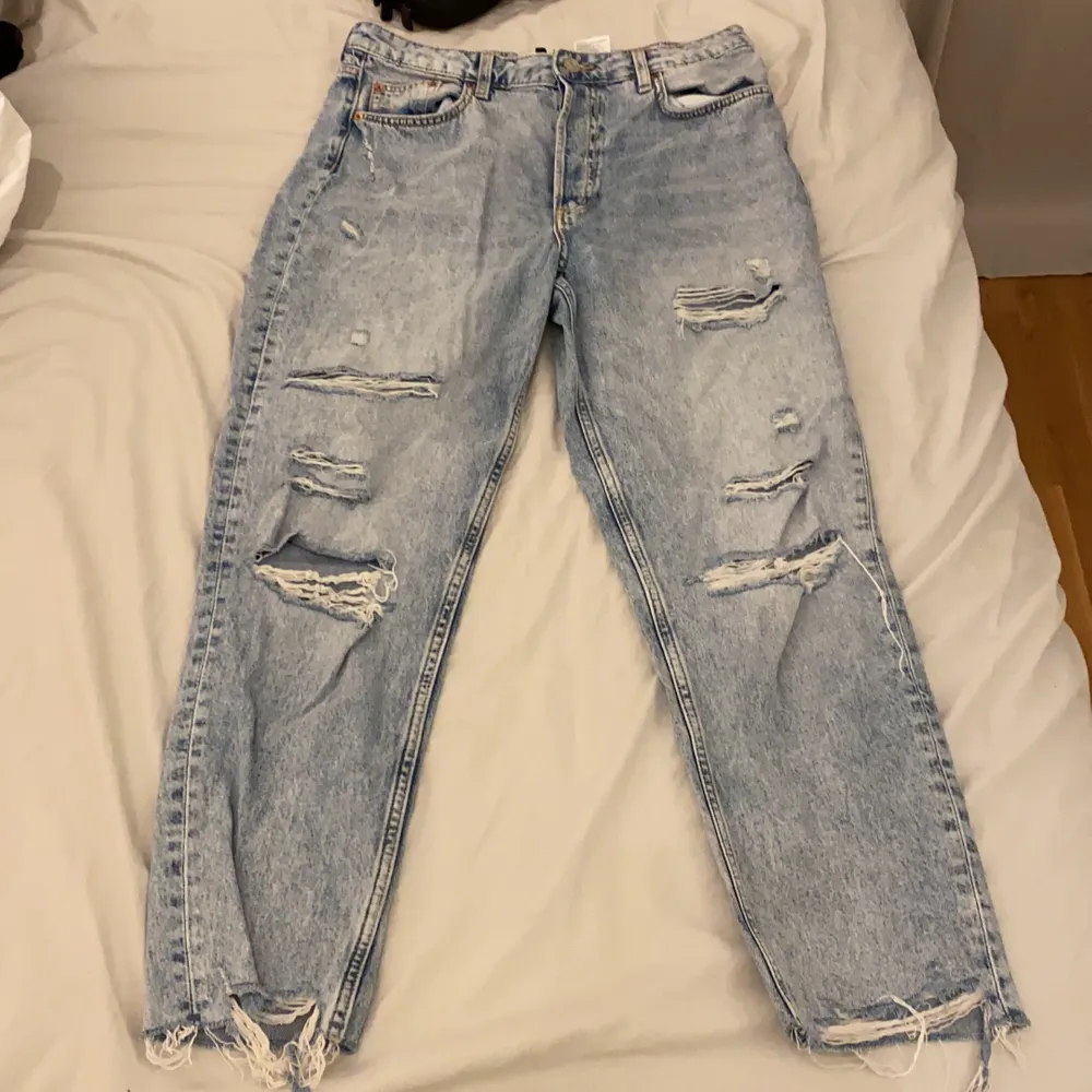 Ett par blå momjeans som har hål. Ganska små i storleken . Jeans & Byxor.