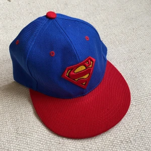 Supermankeps  - Helt oanvänd och i fint skick. Inte min stil längre därav säljer! Justerbar. Köparen står för frakten