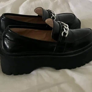 Loafers i lack  med platå  - Sjukt snygga loafers med platå i lack från ASOS. Dessa köptes i fel storlek så dom har aldrig används. Nypris 500 kr. Det är en UK 4 och skulle säga att den passar en med storlek 37. Innermått: 22,5 cm. Man kan även ta bort kedjan rätt lätt (gjort det på min egna!) Säljer dom för 300 kr exklusive frakt🌸